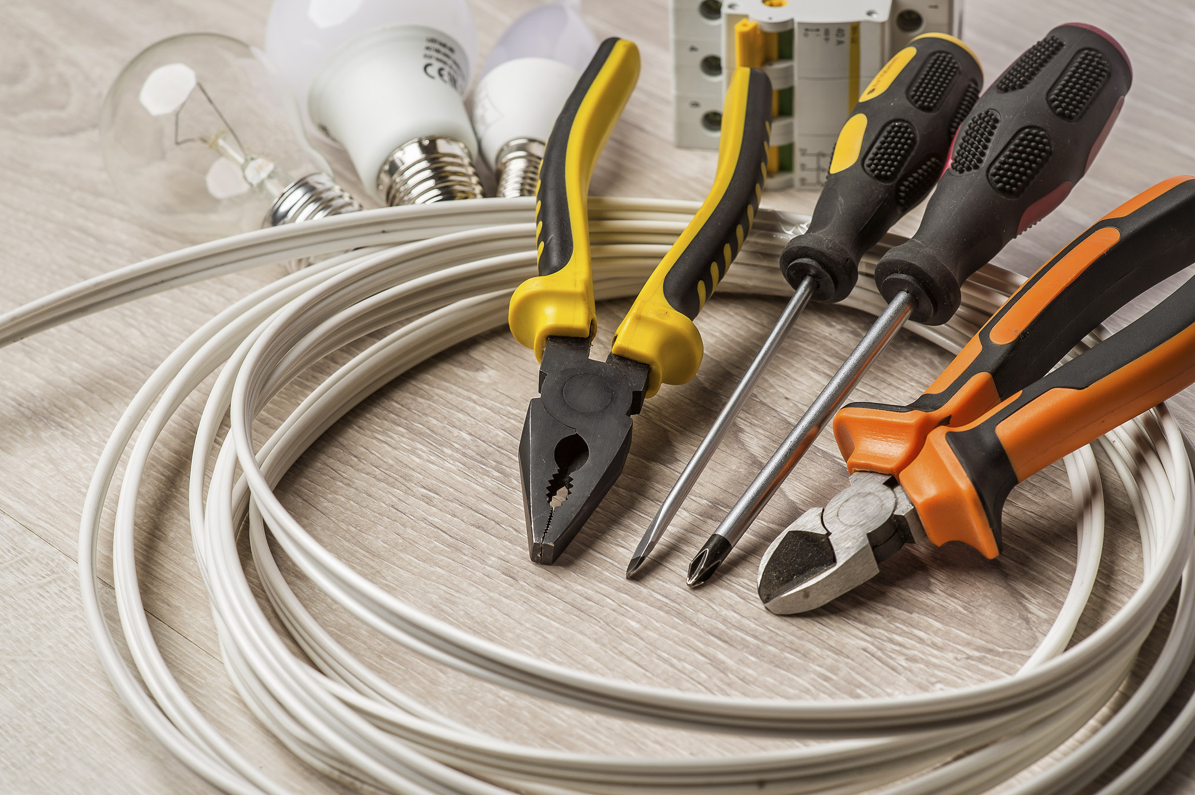 set of electrician tools, a coil of wire and equipment in backgr
