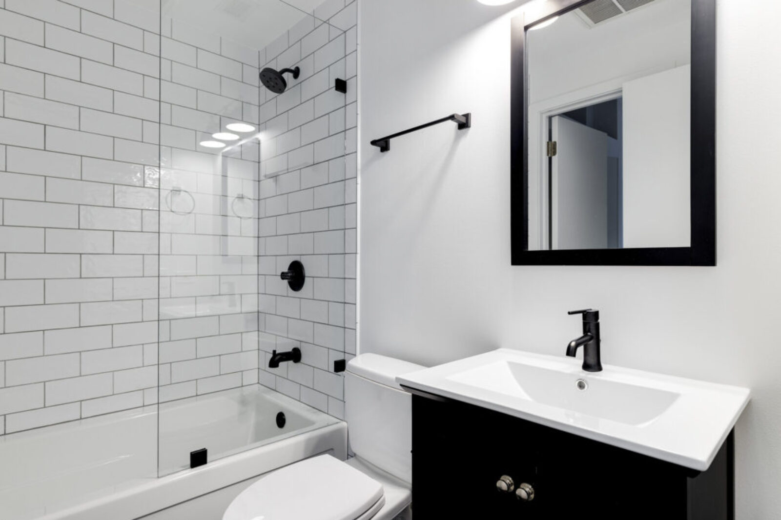 A small modern bathroom with a dark vanity, mirror frame, and ha